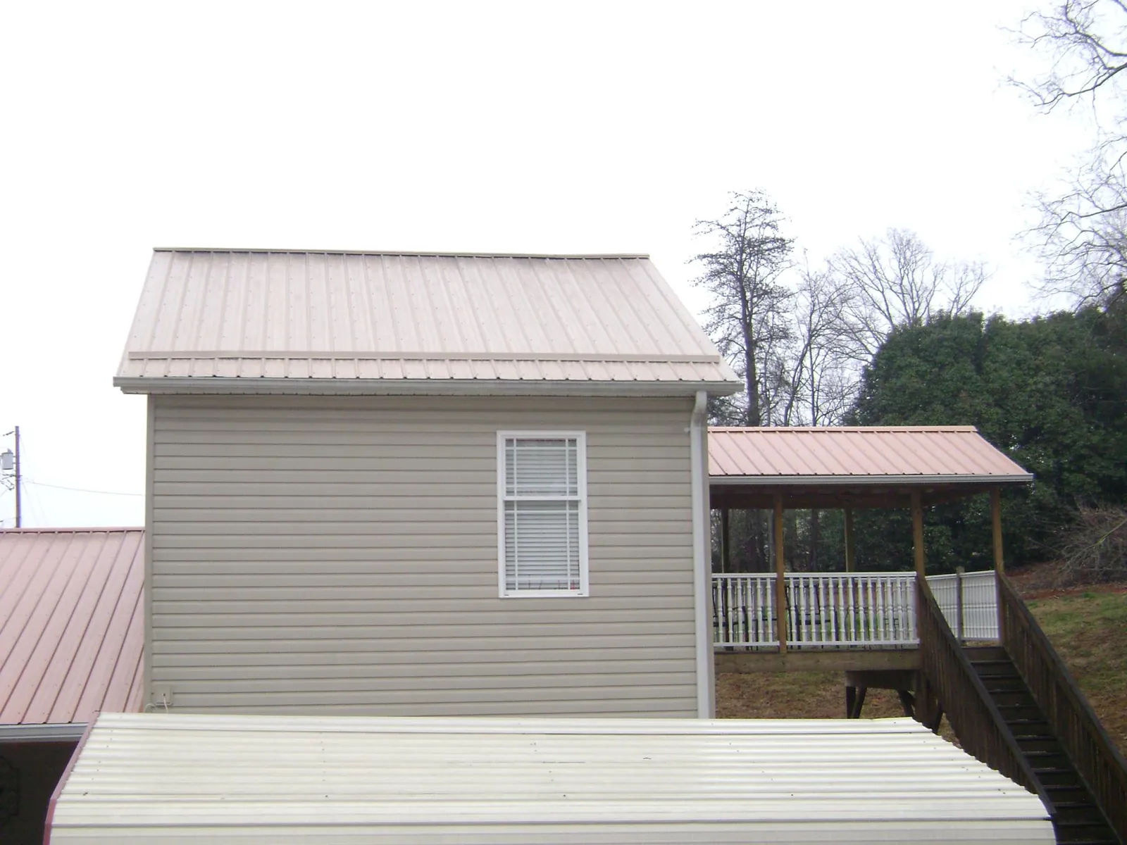 Tan metal roofs on a two story addition and attached porch, from a Roof Replacement job in Mercer Island