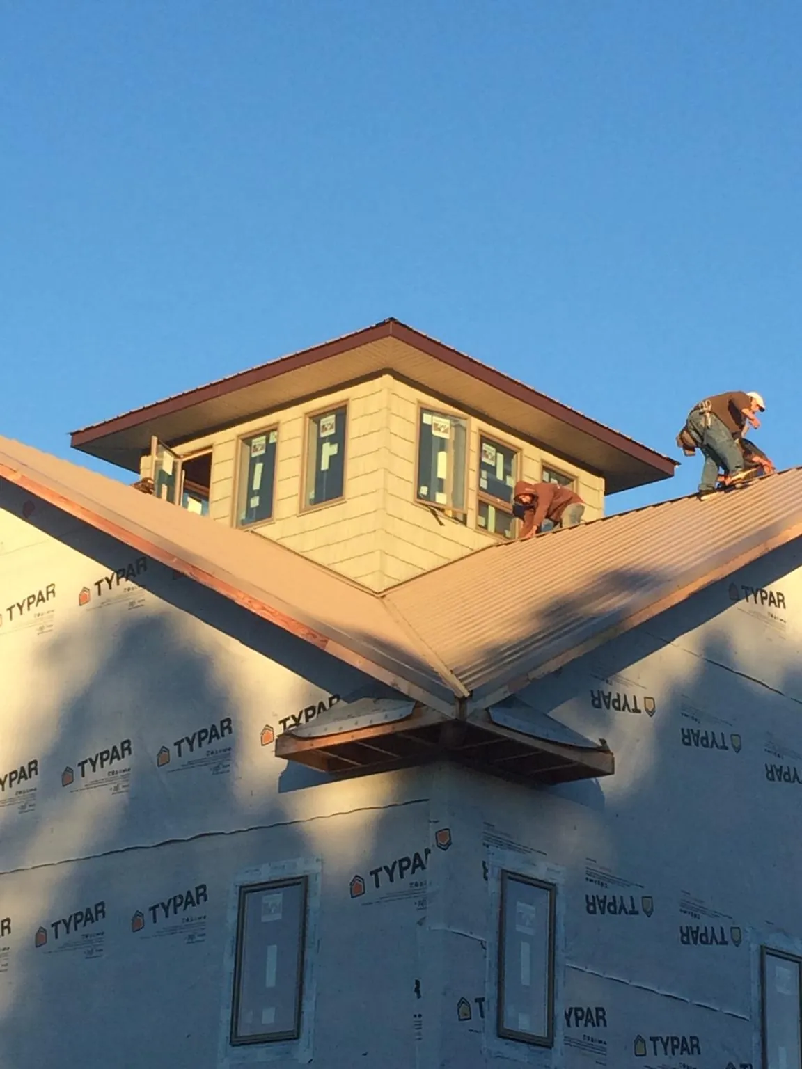 Roofers working around a rooftop cupola on a new metal roof at sunset — Roof Waterproofing in Mercer Island by Roofing Brothers